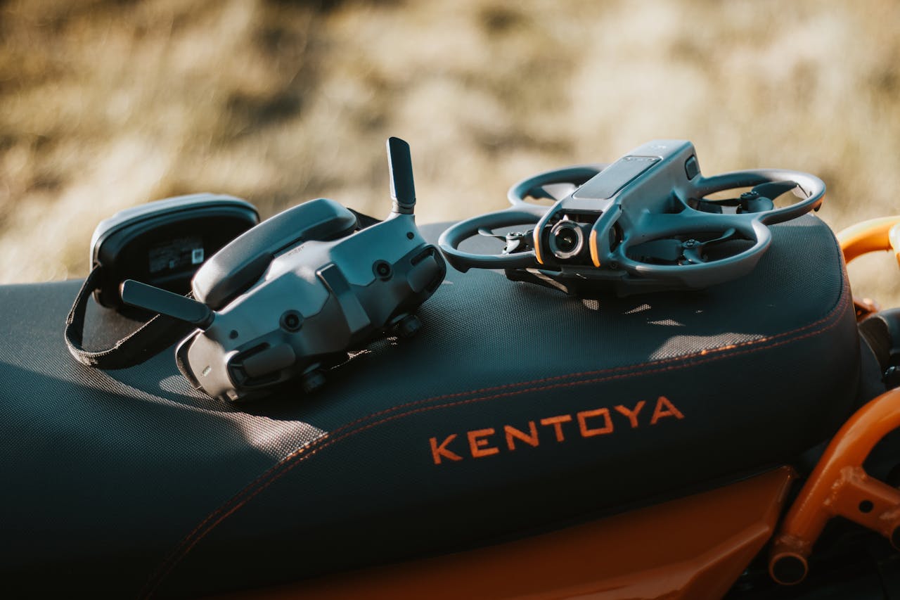 Services FPV drone and goggles placed on a motorcycle seat with 'Kentoya' visible, showcasing outdoor tech setup.