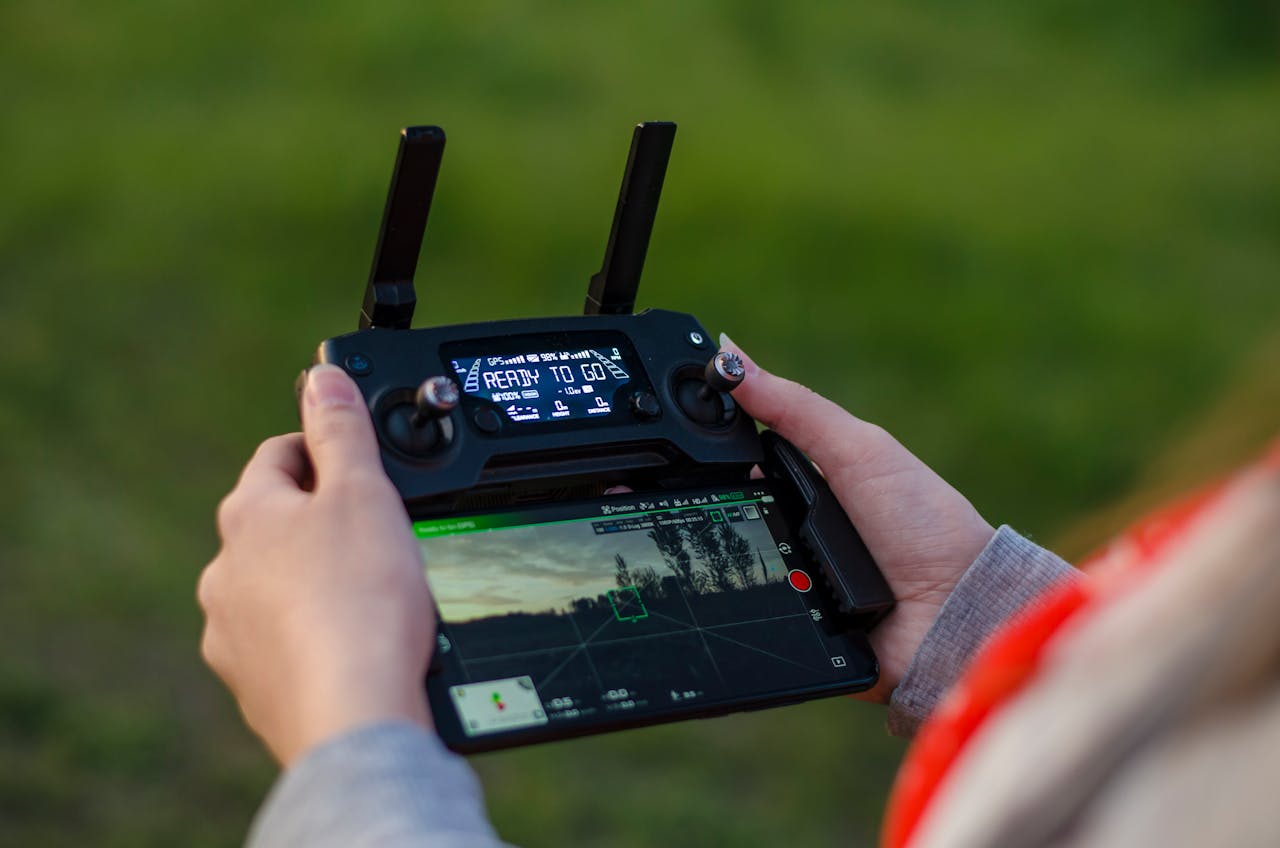 About Close-up of hands holding a DJI drone controller outdoors with green background.