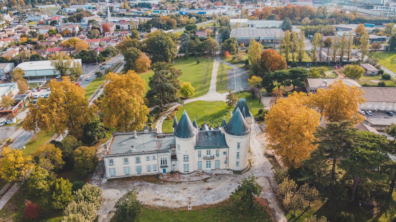 Stunning aerial view of a historic chateau amidst vibrant fall foliage in Bordeaux, France.